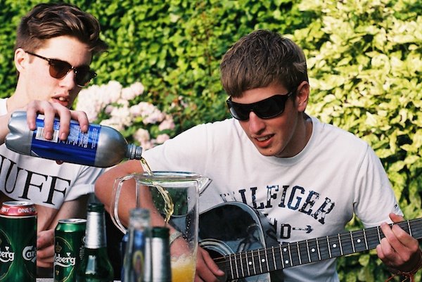 Фотография одного парня, наливающего напиток, и другого, играющего на гитаре, снятая на пленку
