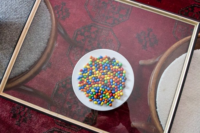 A pane of glass sits above a bowl of m&ms