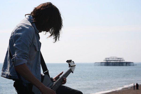 фото мужчины-гитариста, поющего на природе на фоне океана