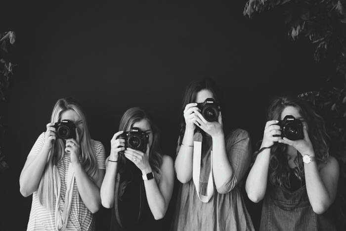 Черно-белая фотография четырех начинающих фотографов с зеркальными камерами