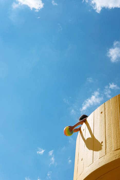 Яркая и воздушная фотография ребенка, играющего в башне на фоне голубого неба, демонстрирующая правило третей в фотографии
