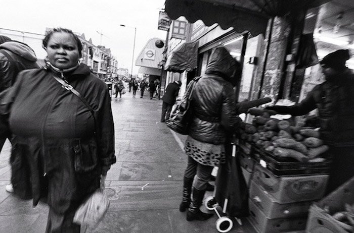 Черно-белое изображение людей, идущих через открытый рынок - съемка от бедра