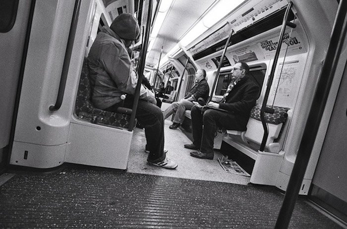 Черно-белое изображение людей в метро - съемка от бедра