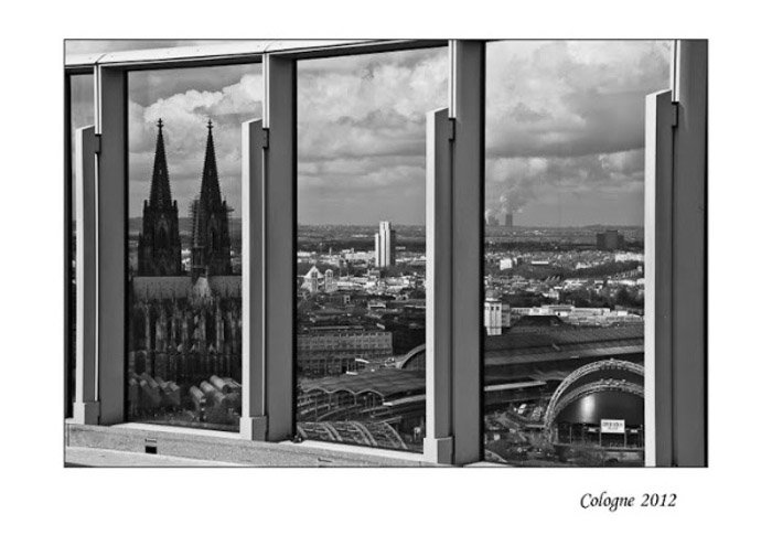 Черно-белая фотография городского пейзажа, снятого через окно