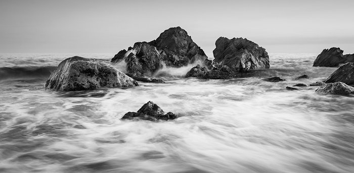 Черно-белое изображение скал на берегу моря, демонстрирующее красивый контраст