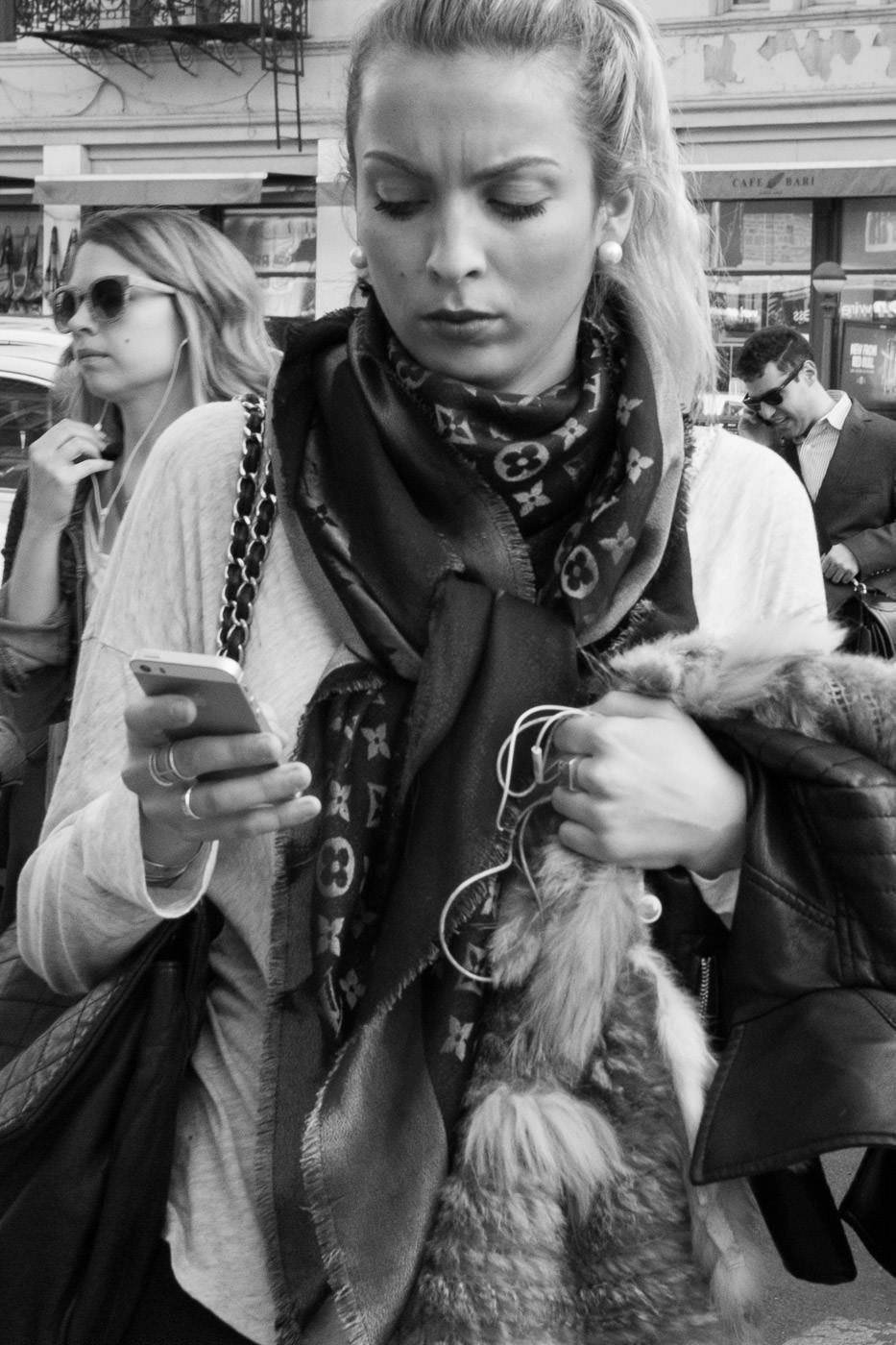 Уличная фотография: Черно-белый портрет женщины с конским хвостом, проверяющей свой телефон