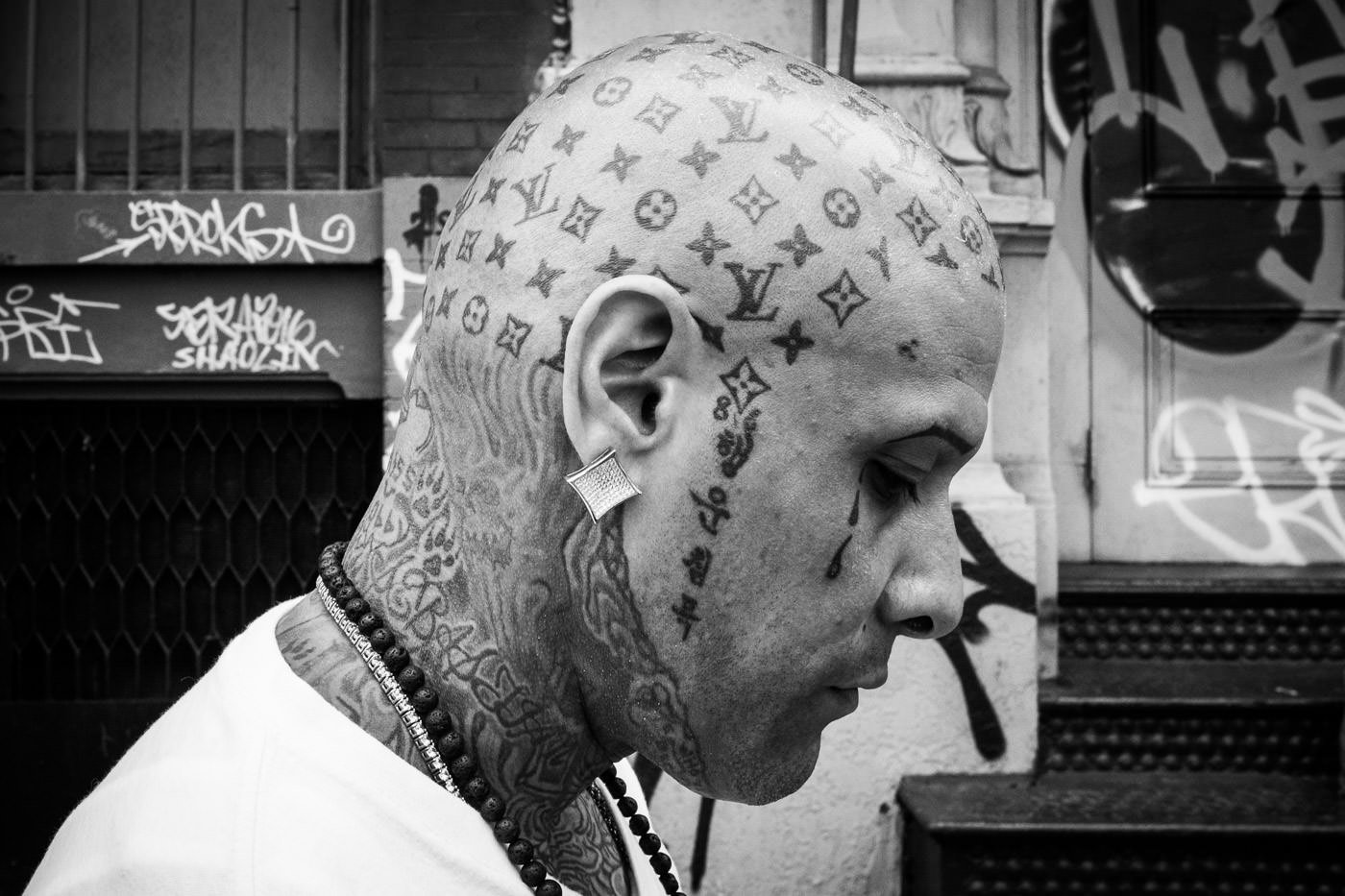 Уличная фотография: портрет мужчины в профиль, демонстрирующий замысловатые татуировки на голове