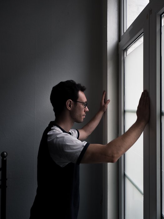 портрет мужчины, смотрящего в окно, освещенный тонким рассеянным светом