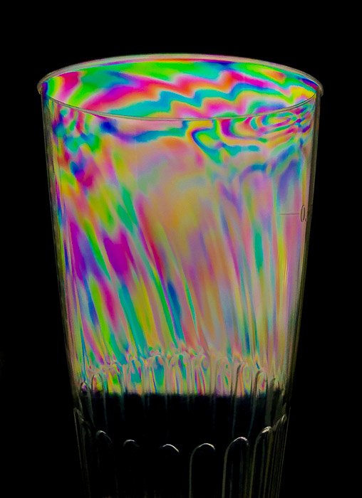 Эффект фотоупругости на прозрачном пластиковом стакане