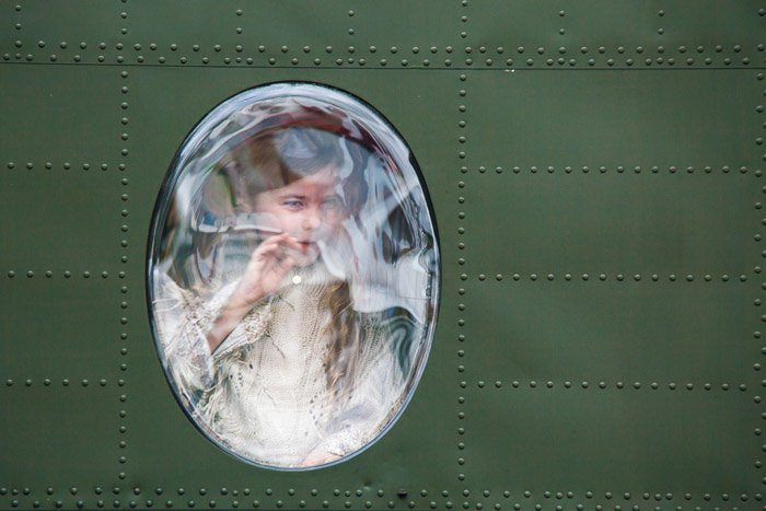 Молодая девушка смотрит в окно военного самолета.