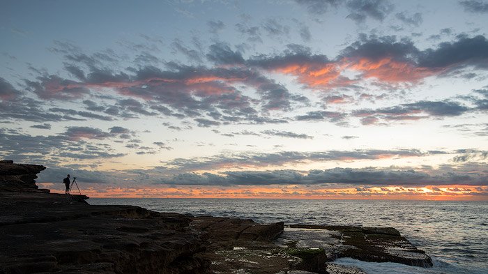 фотограф снимает рассвет у моря