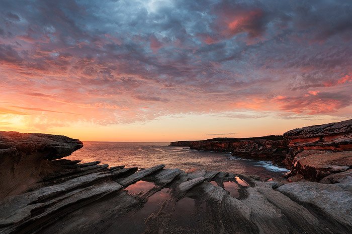 Отражение скалы в прибрежном морском пейзаже на восходе солнца