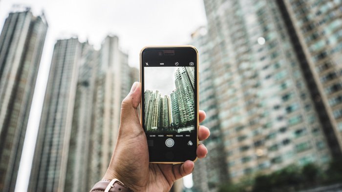 Человек фотографирует небоскребы со смартфона