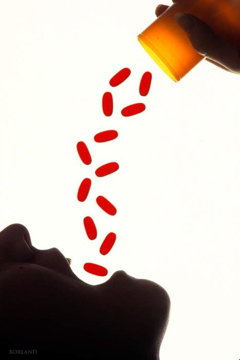 Концептуальная стоковая фотография человека, засыпающего красные таблетки в рот