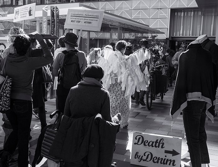 Черно-белая фотография группы протестующих перед зданиями и магазинами