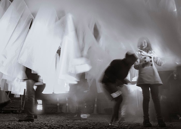 Движение и размытость в документальной фотографии - черно-белая фотография с длинной выдержкой людей, движущихся между белым материалом 