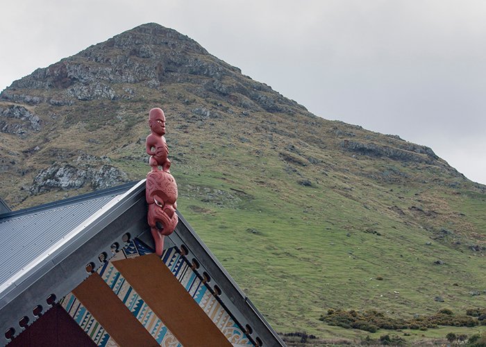 красная резная скульптура аборигенов на крыше перед горой