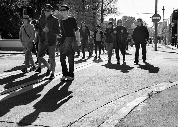 Черно-белая фотография толпы людей, идущих мимо