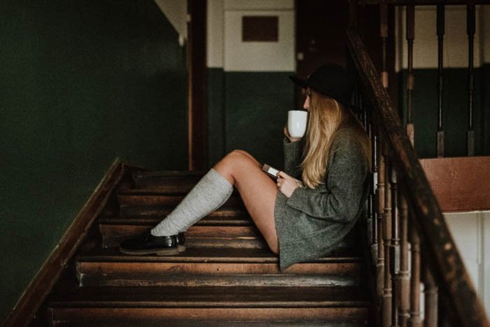 Женская фотомодель, сидящая на деревянной лестнице - композиция модной фотографии