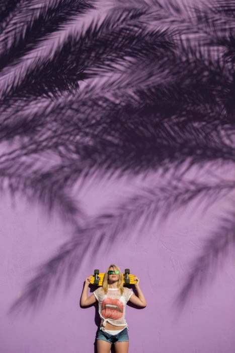 Женская фотомодель позирует на улице со скейтбордом - модная фотокомпозиция