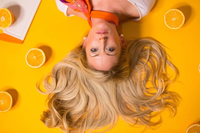 Яркая плоская фотография женской фотомодели, позирующей с лимонами на желтом фоне - композиция модной фотографии