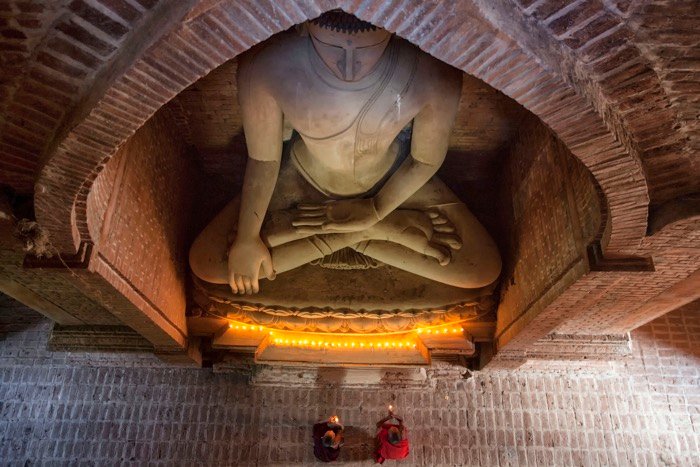 Вид сверху на буддийских монахов, молящихся под статуей Будды - аксессуары для туристической фотографии 