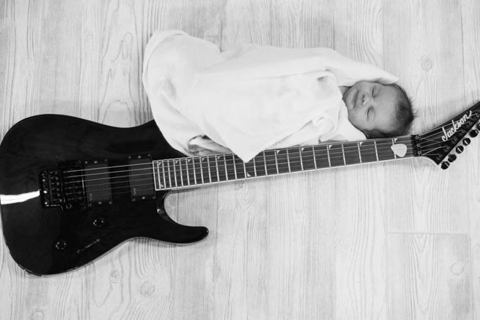новорожденный ребенок позирует рядом с гитарой