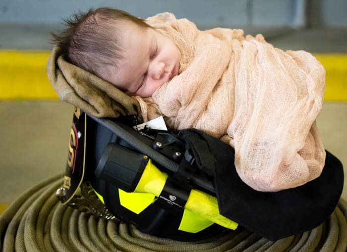 newborn baby in cute helmet prop