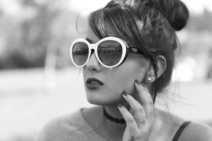 Черно-белый снимок головы модели с отражением в солнцезащитных очках в белой оправе