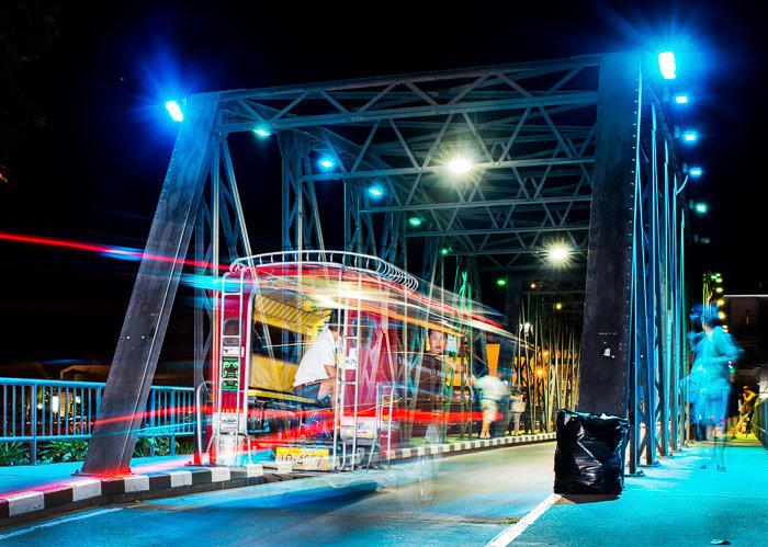 Светлые хвосты трамвая на мосту ночью