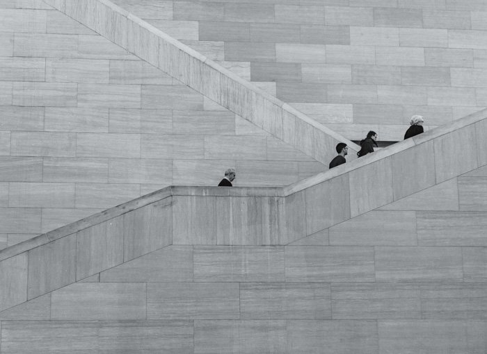 Серый снимок людей, поднимающихся по каменной лестнице