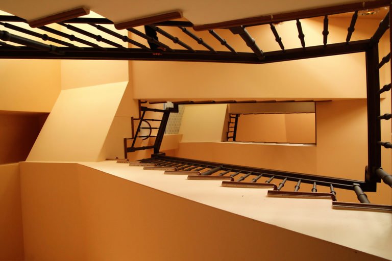 Фотография винтовой желтой лестницы, сделанная снизу