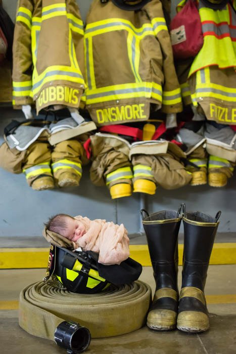 новорожденный ребенок позирует с атрибутикой пожарного