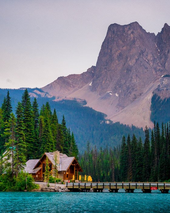 Потрясающая пейзажная фотокомпозиция гор над маленьким домиком, пирсом и озером