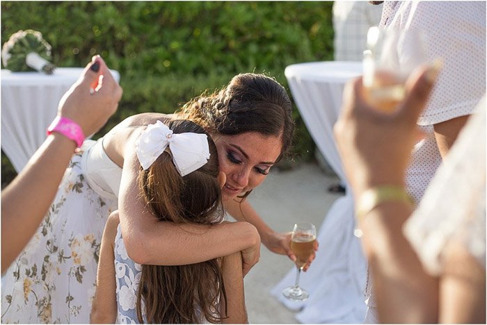 Невеста обнимает юную цветочницу на фоне хлопающих гостей. Любительская свадебная фотография.