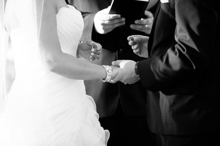 Черно-белая свадебная фотография крупным планом жениха и невесты, произносящих свои клятвы.