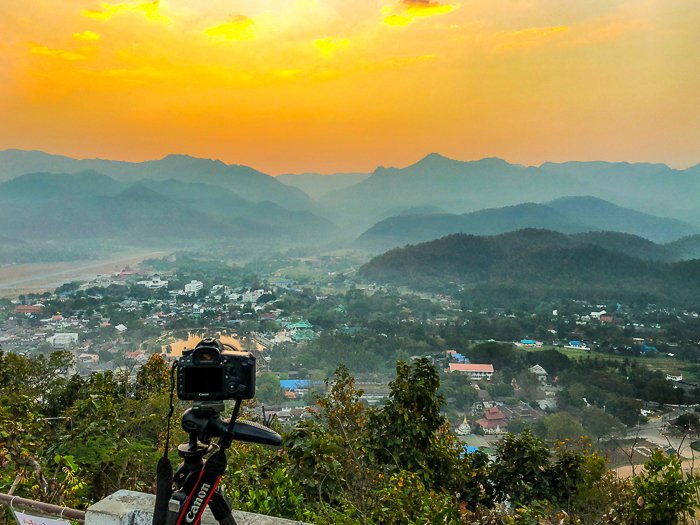 Камера на штативе направлена на потрясающий пейзаж с желтым небом - как заработать на фотографии