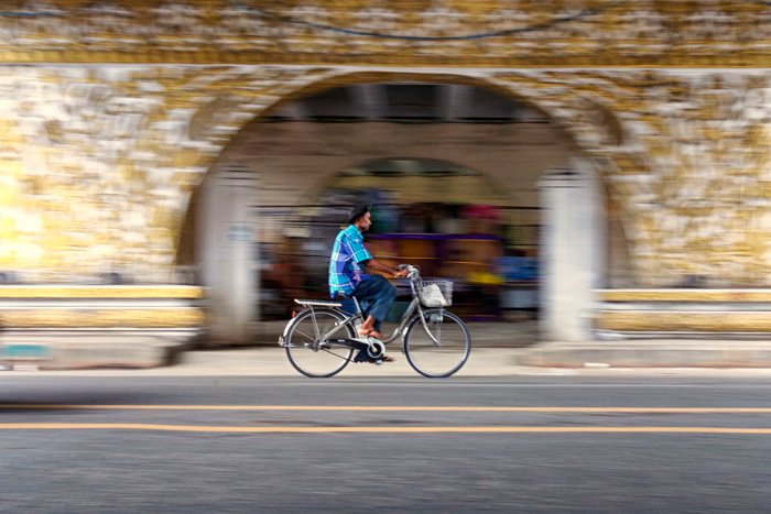 Уличная фотография мужчины на велосипеде с размытым фоном. 