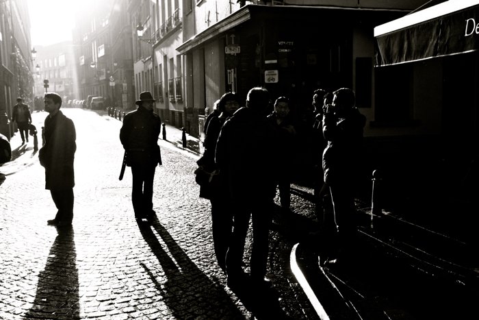 Черно-белая уличная фотография группы разговаривающих людей. 