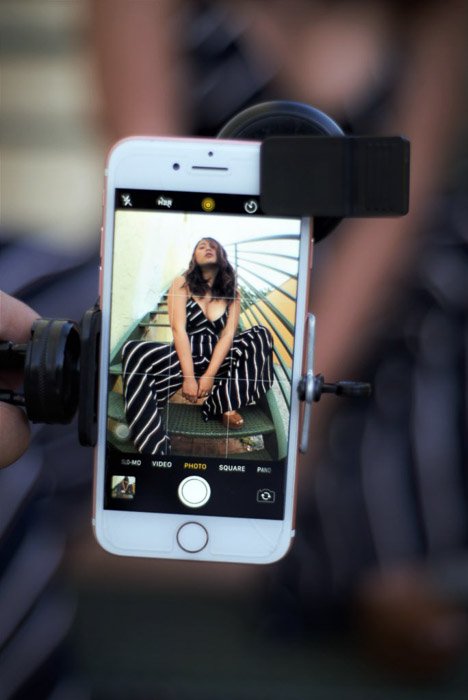 Смартфон с изображением девушки, позирующей на экране, удерживаемый штативным держателем для смартфона - эргономичная установка телефона для модной фотографии