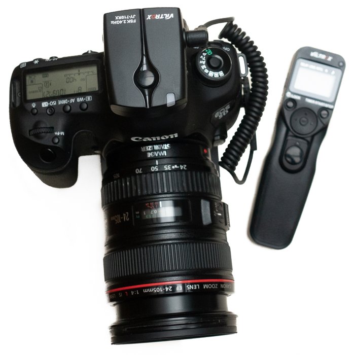 Камера Canon с отдельным аксессуаром интервалометром на белом фоне.