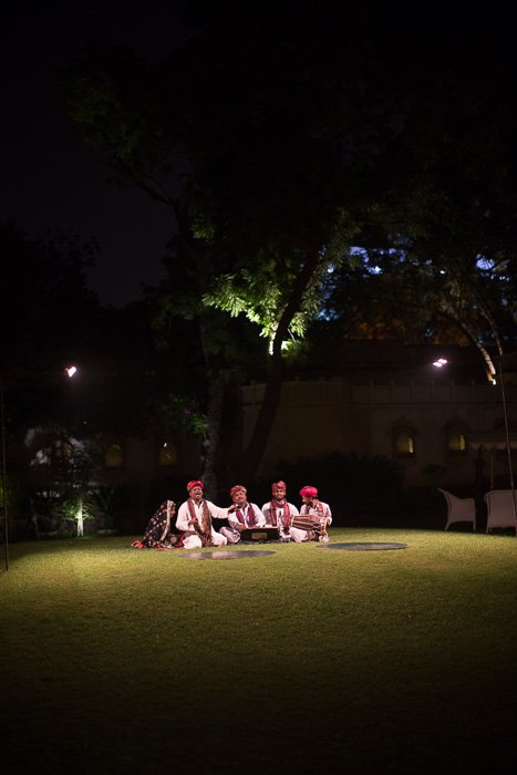 Travel photography of 4 men sitting on the grass under a tree at night.