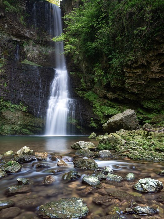 Красивый струящийся водопад, окруженный зеленым мхом и камнями