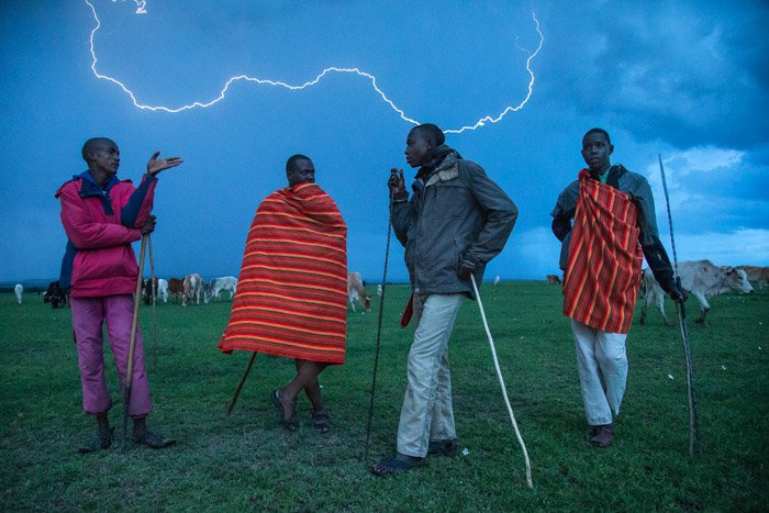 Ночная фотография 4 африканских мужчин, стоящих на открытом воздухе, с молнией на заднем плане