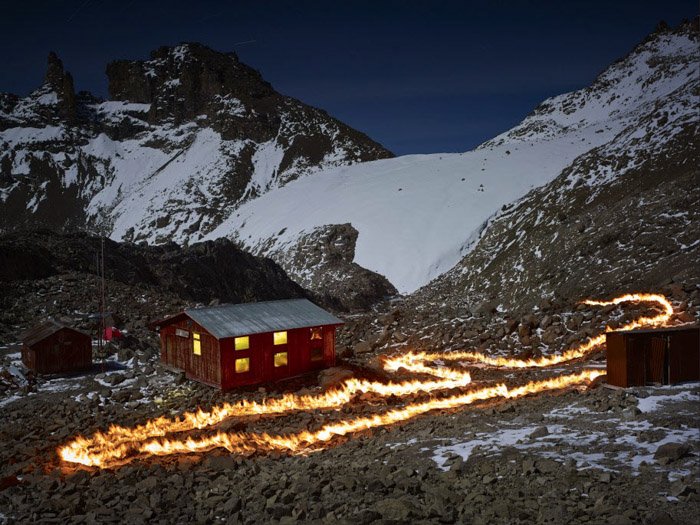 Фотография пожарной тропы у деревянного дома в заснеженном горном ландшафте от Саймона Норфолка. 