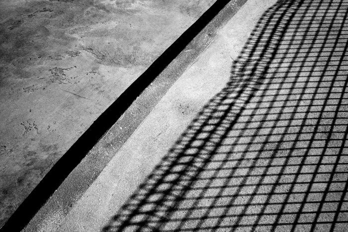 Теневая черно-белая фотография бетона с тенью от забора, сочетающая свет и тень для абстрактной фотографии.