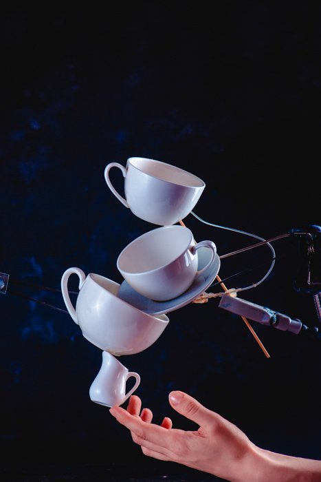 Креативная идея фотографии брызг кофе, балансирующих на темно-синем фоне падающих кофейных чашек