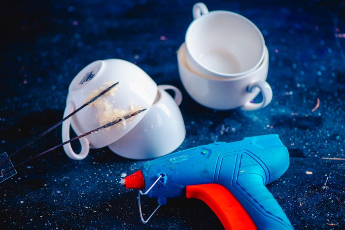 Снимок сверху кофейных чашек и клеевого пистолета на звездном синем фоне для креативного фотопроекта Coffee Splash