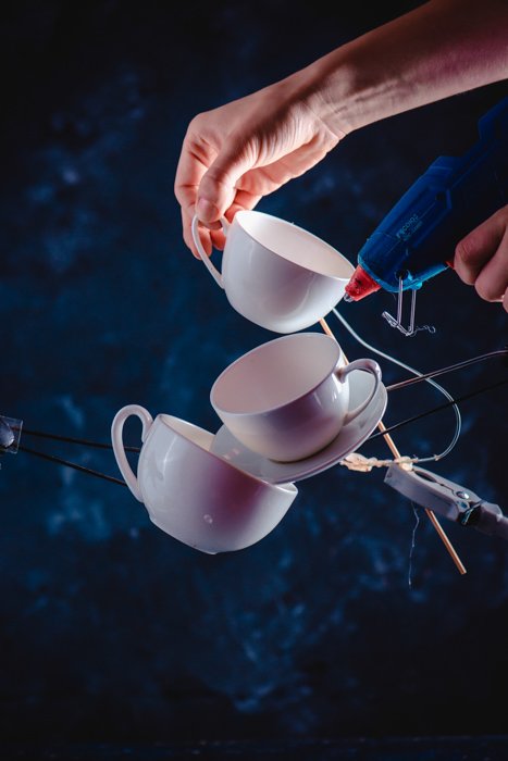 Креативная идея фотографии брызг кофе, балансирующих падающих кофейных чашек на темно-синем фоне