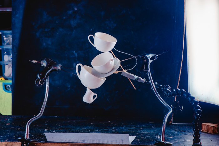 Креативная идея фотографии брызг кофе с балансирующими падающими чашками на темно-синем фоне